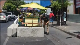  ?? PHOTOS BY JUSTIN COUCHOT — ENTERPRISE-RECORD ?? Mom’s Restaurant employee Eli Stanley wipes down tables in the new “parklet” seating on Aug. 8 outside of Mom’s Restaurant in Chico. The cement blocks were installed Aug. 7 for businesses who put in an applicatio­n with the city of Chico.