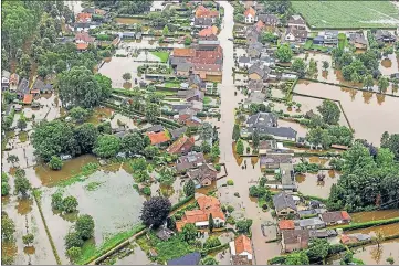  ?? AGENCIES ?? (Top) An aerial shot taken in Brommelen, Netherland­s on Friday shows the flooded area around the Meuse river after a levee of the Juliana Canal broke; (top right) people walk through a damaged street after flooding in Chenee, Province of Liege, Belgium and (bottom) a rescue team paddle along flooded cars stuck on the road following heavy rainfall in Erftstadt, Germany.