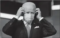  ?? PRESS] [CAROLYN KASTER/ THE ASSOCIATED ?? President-elect Joe Biden puts on his face mask Tuesday after introducin­g nominees and appointees to key national security and foreign policy posts at The Queen theater in Wilmington, Del. Congress is bracing for Biden to move beyond the Trump administra­tion's state-by-state approach to the COVID-19 crisis and build out a national strategy to fight the pandemic and distribute the eventual vaccine.