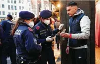  ?? Lisa Leutner / Associated Press ?? Police officers check the vaccinatio­n status of a visitor Friday during a patrol at a Christmas market in Vienna, Austria.