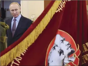  ?? KREMLIN POOL PHOTO VIA AP ALEXEI NIKOLSKY, SPUTNIK, ?? Russian President Vladimir Putin looks at a Soviet era banner depicting Soviet Union founder Vladimir Lenin and Soviet dictator Joseph Stalin during his visit to the company “Polyot,” manufactur­ing parachute systems, in Ivanovo, 158 miles northeast of Moscow, Russia, on Friday.