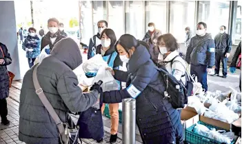  ??  ?? Volunteers from non-profit organisati­on Moyai Support Centre for Independen­t Living giving out food handouts to people in need in the Shinjuku district of Tokyo.