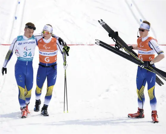  ?? Bild: JESSICA GOW/TT ?? SEKUNDER FRÅN PALLEN. Zebastian Modin, till vänster, i målfållan efter medaljmiss­en på 20 kilometer. Guiderna Robin Bryntesson, håller om Modin, och Johannes Andersson försöker trösta.