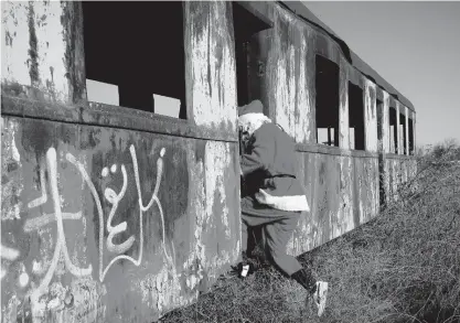  ?? AP ?? A charity worker wearing a Santa Claus costume jumps out of an abandoned train carriage after delivering Christmas presents to a poor family on the outskirts of Brasov, Romania, last Sunday.