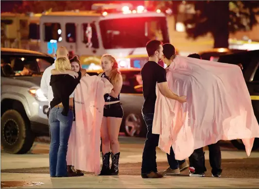  ?? Photo: AP ?? People comfort each other near the scene in Thousand Oaks, California, where a gunman opened fire Wednesday (US time) inside a country dance bar crowded with hundreds of people on “college night,” killing at least 12 people and injuring around a dozen. The Ventura County sheriff’s spokesman says the gunman was found dead in the bar