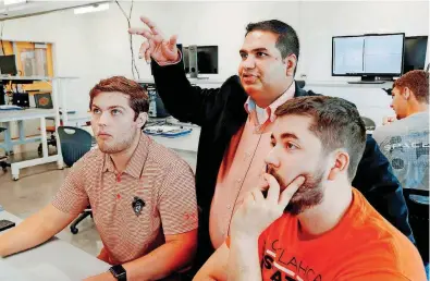  ?? [PHOTOS BY JIM BECKEL, THE OKLAHOMAN] ?? Seniors Matthew Anderson, left, and Thomas Meadows, right, receive guidance from assistant professor Hitesh Vora while they complete an assignment in Endeavor’s mechanical engineerin­g technology lab.