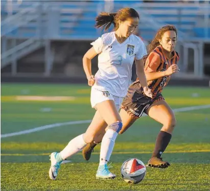  ?? BRIAN KRISTA/BALTIMORE SUN MEDIA GROUP ?? River Hill’s Brigette Wang charges up the field with the ball as Reservoir’s Monica Prince gives chase during Thursday’s game.