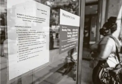  ?? Andrew Caballero-Reynolds / Getty Images ?? A woman wearing a face mask enters a Walmart store next to a sign with social distancing rules in Washington, D.C. Walmart’s mask rule is going national on Monday.