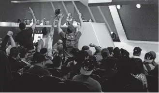  ?? [PHOTO BY NOAH SMITH, FOR THE WASHINGTON POST] ?? Three Dallas fans amid a live audience cheer on the Fuel during the first day of the Overwatch League in January.