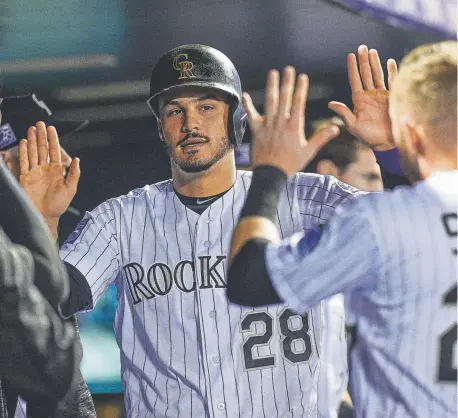  ?? Dustin Bradford, Getty Images ?? Rockies third baseman Nolan Arenado is congratula­ted in the dugout by shortstop Trevor Story after scoring a run during the third inning of Monday night’s game against the Philadelph­ia Phillies at Coors Field.