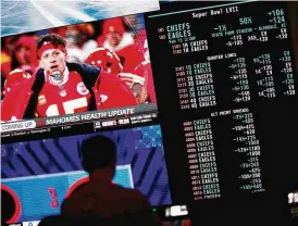  ?? JOHN LOCHER / AP ?? A person gambles as betting odds for the Super Bowl are displayed on monitors at the Circa resort and casino sports book Friday in Las Vegas.