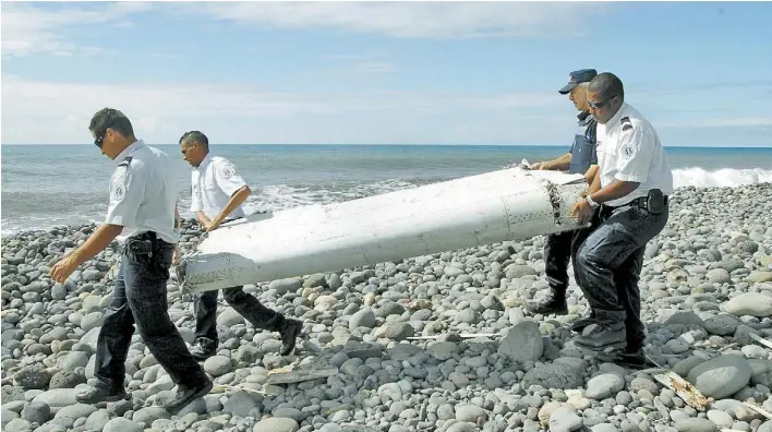  ?? EFE ?? Resto. Policías de la isla de La Reunión, en el Océano Indico, trasladan una parte de lo que sería un ala de un Boeing 777, similar al de Malaysia Airlines desparecid­o en marzo de 2014.