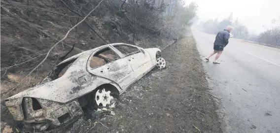  ?? Picture: EPA ?? TORCHED. A destroyed car on the side of the road after a raging bush fire swept through the seaside town of Knysna.