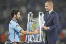  ?? AP file photo ?? UEFA president Aleksander Ceferin hands the trophy to Manchester City captain Ilkay Gundogan after the Champions League final on June 11.