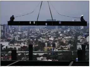  ?? (AP) ?? Constructi­on workers ride on a beam hanging from a crane at the constructi­on site of a residentia­l high rise building in Mexico City in this June file photo.