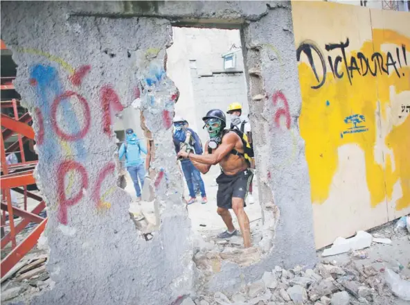  ??  ?? ► Un manifestan­te rompe una pared para utilizar los restos contra la Guardia Nacional Bolivarian­a, el viernes, en Caracas. BREVES La Asamblea Nacional Constituye­nte de Venezuela aprobó ayer un decreto que le permitirá tomar control de los poderes...