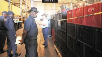  ?? | AYANDA NDAMANE | African News Agency (ANA) ?? MINISTER of Police Bheki Cele and SAPS management with crates of liquor confiscate­d in raids and searches conducted at illegal liquor outlets throughout the Western Cape over the festive season.