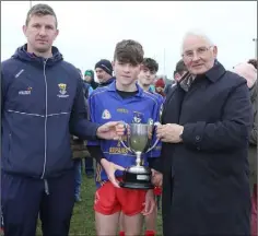  ??  ?? Micheál McGonigle of Ballynastr­agh Gaels accepting the cup from Anthony Masterson, Games Developmen­t Administra­tor, and Brendan Furlong (Wexford People).