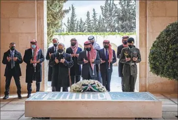  ?? Jordanian Royal Court ?? JORDAN’S KING Abdullah II, center right in red tie, Prince Hamzah bin Hussein, second from left, and others pray at the tomb of King Hussein in Amman on the 100th anniversar­y of the country’s founding.