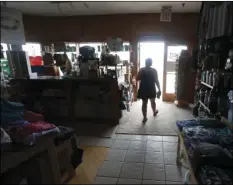  ?? THE NEWS & OBSERVER VIA AP ?? Tara Clark shops at Ocracoke Outfitters in Hatteras, N.C. on Friday. Even though the power was out, Clark and her kids, who are from Indianapol­is, were able to shop and buy souvenirs. The store stayed open without power but only accepted cash for...