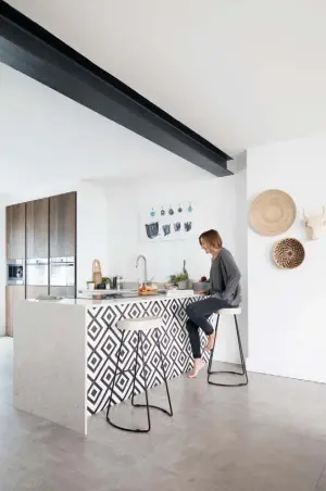  ??  ?? KITCHEN
Annette re-drew the plans for this space when she discovered an ex-display kitchen with tall, dark wood cupboards and high-end appliances, that was ideal for concealed storage. Fixing lightweigh­t vinyl floor tiles to the back of the peninsula makes a stylish focal point in the open-plan room. A pair of bar stools from Cox &
Cox have metal legs that pick out the black in the graphic monochrome tile pattern, while woven baskets that came from Cape Town bring a natural touch