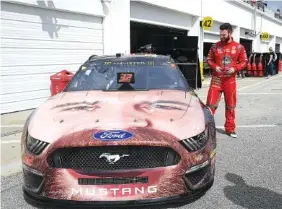  ?? AP PHOTO/PHELAN M. EBENHACK ?? Corey LaJoie looks at his likeness on the hood of his car in the garage area Saturday during a practice session for today’s Daytona 500, the 2019 NASCAR Cup Series opener.