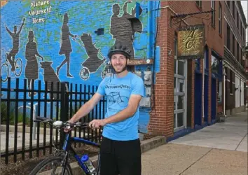  ?? Nate Guidry/Post-Gazette ?? Jesse Descutner, assistant Main Street manager for the Northside Leadership Conference, stops on Foreland Street in Deutschtow­n near Allegheny City Brewery, one of 14 businesses participat­ing in the We Like Bikes! initiative.