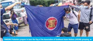  ??  ?? YANGON: Protesters prepare to burn the flag of the Associatio­n of Southeast Asian Nations (ASEAN) grouping, as they take part in a flash mob demonstrat­ion against the military coup in Yangon yesterday. — AFP