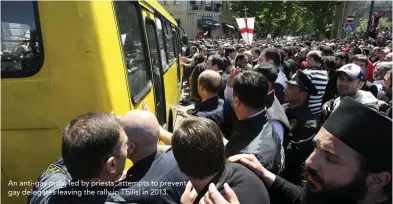  ??  ?? An anti-gay mob, led by priests, attempts to prevent gay delegates leaving the rally in Tbilisi in 2013.