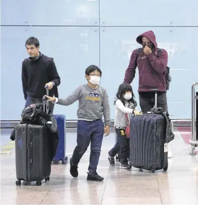  ?? ELISENDA PONS ?? pareja de niños asiáticos, en la terminal de llegadas del aeropuerto de El Prat.