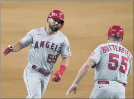  ?? TONY GUTIERREZ — THE ASSOCIATED PRESS ?? The Angels’ Jack Mayfield (59) and third base coach Brian Butterfiel­d celebrate Mayfield’s solo home run in the fifth inning of Wednesday night’s game at Texas.