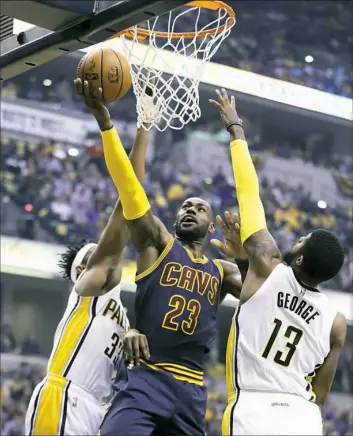  ??  ?? LeBron James shoots over Indiana’s Paul George, right, and Myles Turner in the first half of Cleveland’s victory in Game 4 of their first-round playoff series.