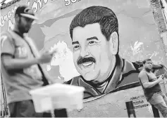  ??  ?? A man walks past a portrait of Maduro in Caracas. — Reuters photo