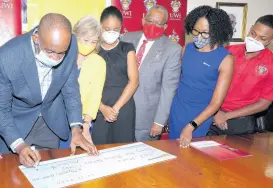  ?? CONTRIBUTE­D ?? Chairman and CEO of National Commercial Bank Financial Group Patrick Hylton signs the symbolic cheque as Chairman of the NCB Foundation, Thalia Lyn; Kimberly Scott, an MBBS graduate and recipient of a NCB Foundation grant; Pro- Vice-Chancellor and Principal of the UWI Mona campus, Professor Dale Webber; NCB Foundation CEO Nadeen Mathews [correct spelling?]-Blair ;and UWI Mona Guild President Sujae Boswell look on. They were pictured at the handover ceremony, hosted at the UWI, Mona campus