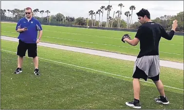  ?? TAMARA LUSH/THE ASSOCIATED PRESS ?? Ben Hansen, left, chief technology officer of Motus Global, watches data on a hand-held device as Pirates prospect Matt Benedict throws at the team’s minor league complex.