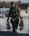  ?? AP PHOTO ?? A member of U.S.-backed Syrian Democratic Forces carries explosives at a stadium that that was the site of Islamic State fighters’ last stand in the city of Raqqa, Syria.