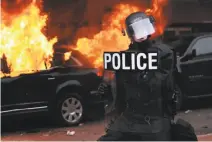  ?? Spencer Platt / Getty Images ?? A police officer secures the area where a car was set on fire during a protest after President Trump was sworn in.