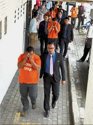  ??  ?? In a spot: MACC officers escorting the suspects held in the Sabah Railway Department probe at the Kota Kinabalu court house.