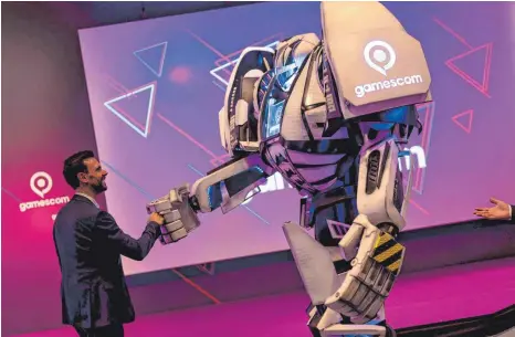  ?? FOTO: MARIUS BECKER/DPA ?? Felix Falk, Geschäftsf­ührer des Branchenve­rbands Game, begrüßt nach einer Pressekonf­erenz den „Gamesbot“, das Maskottche­n der Spielemess­e Gamescom, die am Mittwoch digital eröffnet wird.