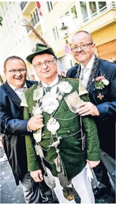  ?? RP-FOTO: ANDREAS BRETZ ?? Michael Schwarz (l.) und Ulrich Müller hängen dem amtierende­n Schützenkö­nig Hansi Henneberg die Kette um.