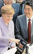  ?? Foto: imago ?? Angela Merkel und Japans Premier Shin zo Abe lassen sich von einem Roboter arm Sushi servieren.