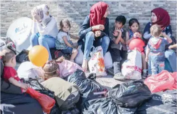  ?? — AFP ?? Syrian refugees and children wait at the Masnaa crossing on the Lebanon-syria border on Saturday, before their evacuation from Lebanon back to Syria.