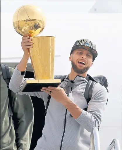  ?? ANDA CHU — STAFF PHOTOGRAPH­ER ?? Warriors’ guard Stephen Curry holds the Larry O’Brien NBA Championsh­ip Trophy as he exits their plane as they arrive back in Oakland.