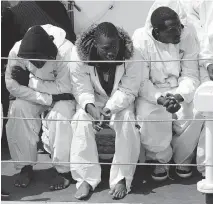 ?? ALESSANDRA TARANTINO/THE ASSOCIATED PRESS ?? Migrants wait to disembark from an Italian Coast Guard ship on Friday. EU leaders are launching a military operation against human trafficker­s in Libya.