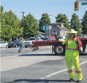  ?? FRANCIS GEORGIAN ?? A road crew member puts out the “slow down, drivers” hand signal along a major artery in east Vancouver on Wednesday. Parts of East 1st Avenue will be fenced off for months this summer.