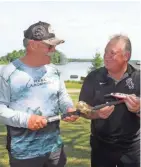  ?? PAUL A. SMITH ?? Joe Weiss (left) exchanges a rod, reel and lure with Jerry Ewert on the grounds of Lost Land Lake Resort near Hayward on July 11.