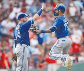  ?? The Associated Press ?? Toronto Blue Jays right fielder Jose Bautista (19) leaps as he celebrates with first baseman Justin Smoak (14) after defeating the Boston Red Sox 8-6 in Boston on Thursday.