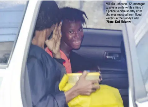  ?? (Photo: Karl Mclarty) ?? Mikaila Johnson, 12, manages to give a smile while sitting in a police vehicle shortly after she was rescued from flood waters in the Sandy Gully.