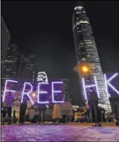  ?? Mark Schiefelbe­in The Associated Press ?? Pro-democracy protesters use illuminati­on lights to form a slogan as they attend a prayer rally Saturday at Edinburgh Place in Hong Kong.