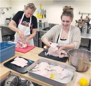  ?? SUPPLIED PHOTO ?? Schoolhaus Culinary Arts School Coordinato­r Teisha Huff (right) and a student join in preparing a chicken for cooking. Students feast on the fruits of their labours following the class.